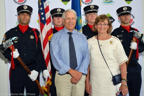 A picture of Stamford's mayor in front of a line of firemen during a groundbreaking ceremony